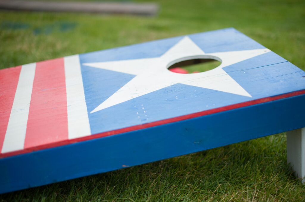 a blue, white and red cornhole game sitting in the grass.