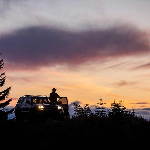 a man sitting on the roof of a van at sunset.