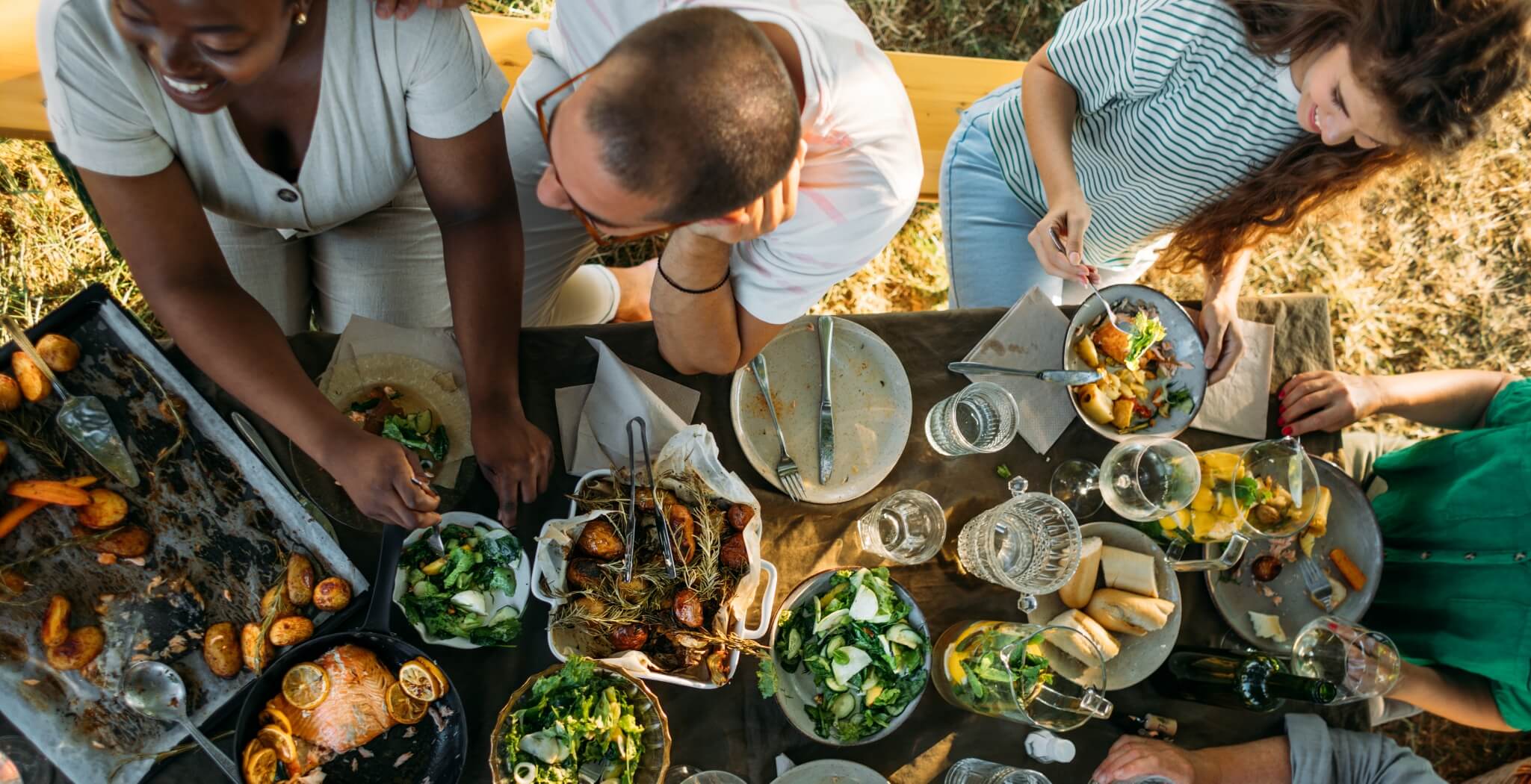 a group of people standing around a table filled with food.